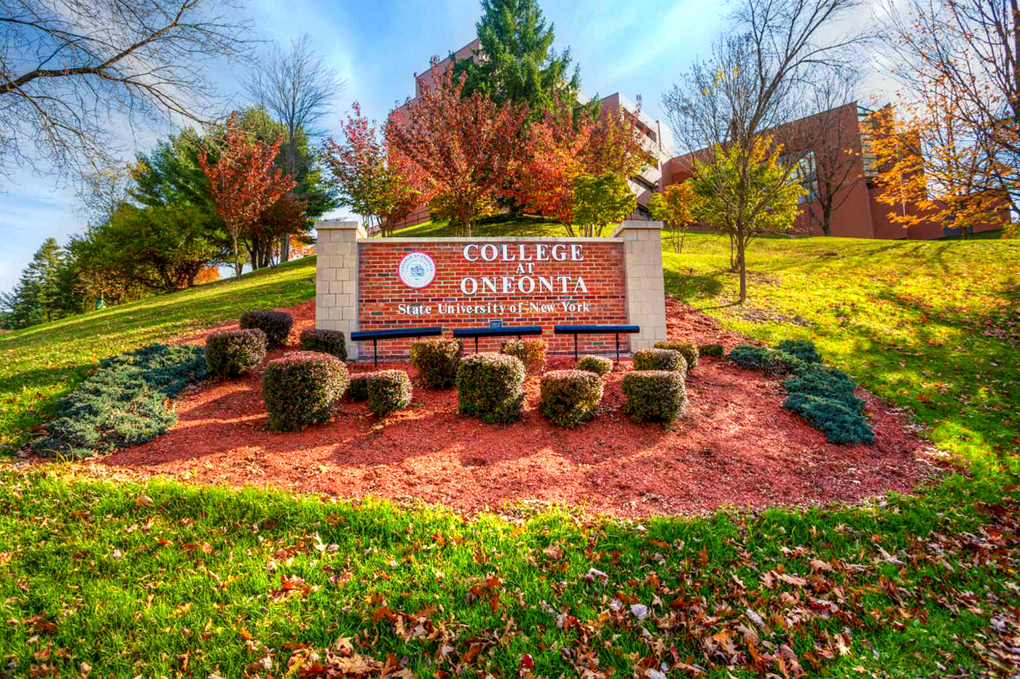 SUNY Oneonta campus entrance sign surrounded by autumn landscaping.