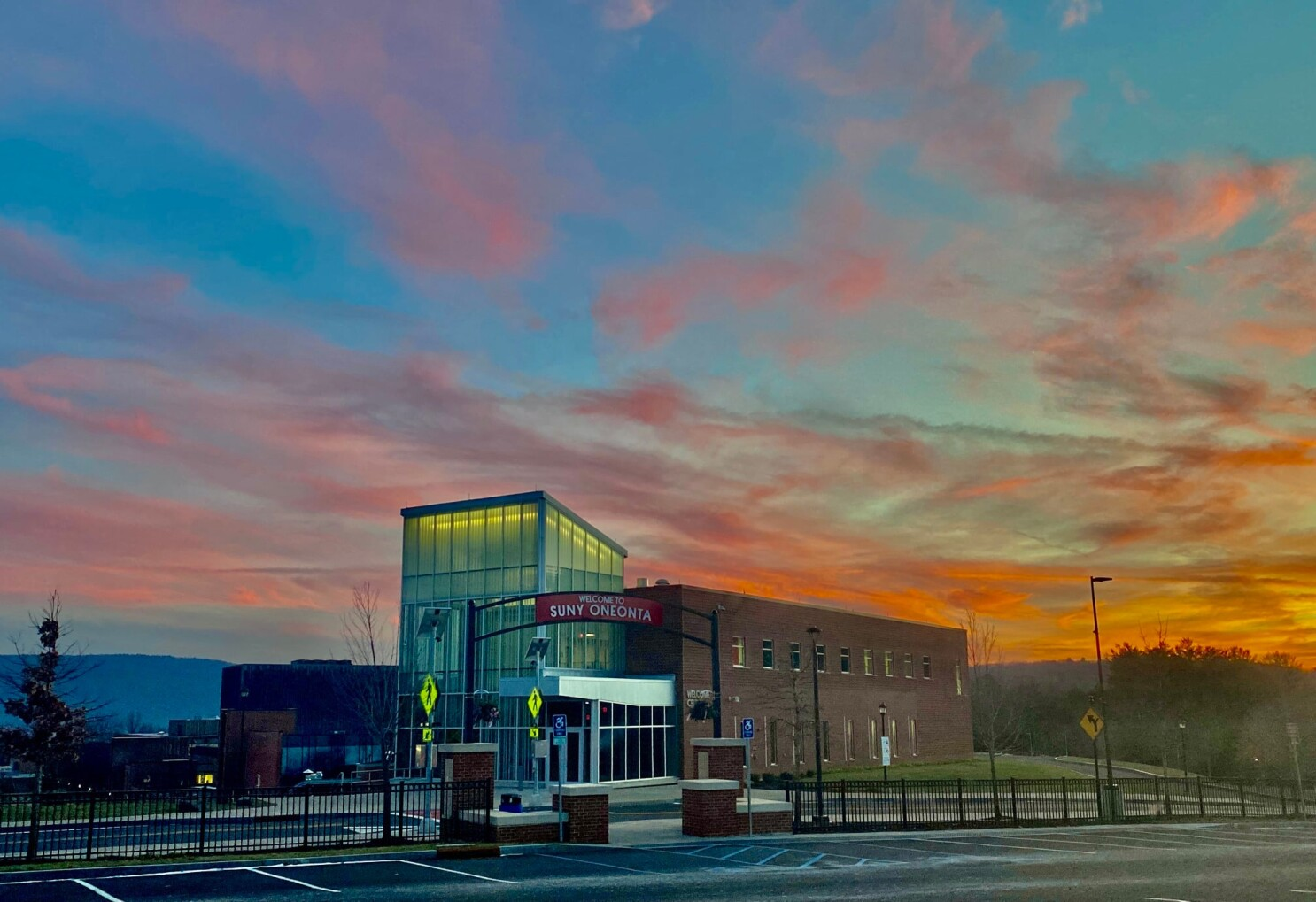 SUNY Oneonta campus building beneath a colorful sunset.