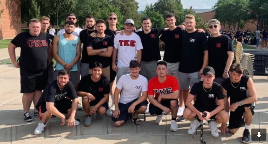 Sigma-Epsilon brothers gathered outdoors near trees.